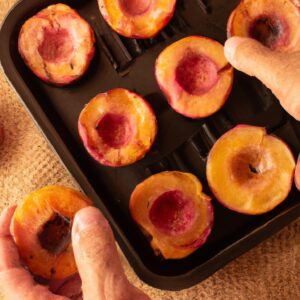 Uma fotografia de pêssegos assados na airfryer. Os pêssegos são cortados ao meio, sem caroço e assados até ficarem macios e caramelizados. Eles são polvilhados com canela e servidos com uma colher de sorvete de baunilha.
