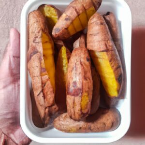 Imagem de batatas-doces fatiadas e crocantes em uma cesta de fritadeira, com um fundo desfocado de uma bancada de cozinha.