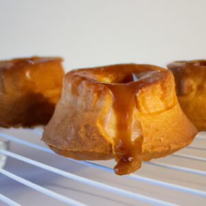 Imagem de um petit gâteau de doce de leite cozido na Airfryer. O bolinho está em uma forma de silicone e tem uma crosta dourada crocante. O doce de leite está borbulhando e derretendo no centro do bolinho. A imagem é tirada de cima e o fundo é branco.