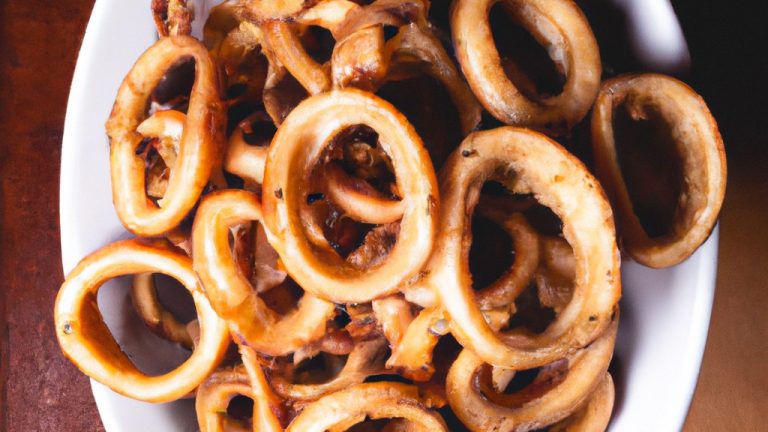 Foto de um polvo inteiro cozido em uma Airfryer. O polvo tem uma cor marrom dourada e está enrolado em um prato. Há uma tigela de molho ao lado do polvo.