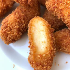 Foto de uma ponta de alcatra assada em uma airfryer. A carne está dourada e suculenta, com um interior rosa claro. A panela da airfryer é visível ao fundo, com uma grade de metal por cima.