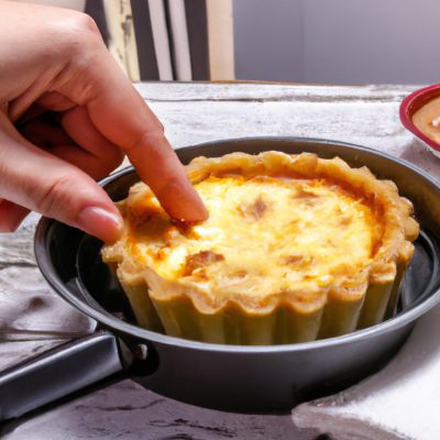 Imagem de uma quiche fit assada em uma airfryer. A quiche é feita com uma crosta de grão integral e recheada com ovos, vegetais e queijo. A quiche é coberta com uma crosta dourada e escamosa.