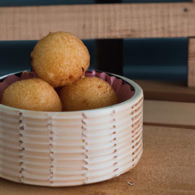Uma imagem de bolinhos de arroz crocantes e dourados feitos na Airfryer. Eles são feitos com apenas 2 ingredientes: arroz cozido e óleo. Os bolinhos são servidos em um prato com um molho de soja opcional.