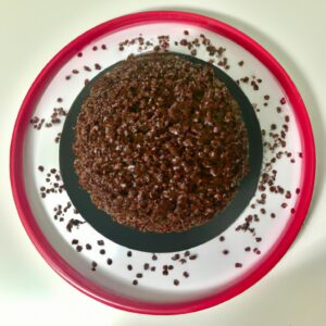 Foto de um grande bolo de brigadeiro cozido em uma fritadeira elétrica. O bolo é marrom escuro e coberto com uma camada de brigadeiro cremoso.