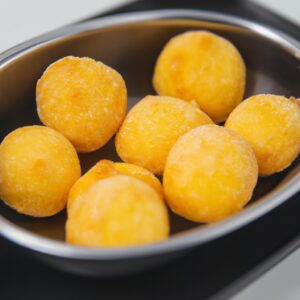 Imagem de medalhões de batata bolinha recheados cozidos em uma Airfryer. Os medalhões são crocantes por fora e macios por dentro, recheados com uma mistura cremosa de queijo, ervas e temperos.