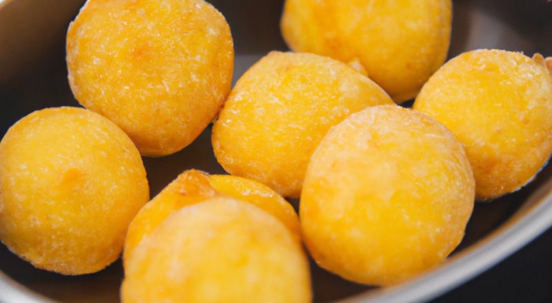 Imagem de medalhões de batata bolinha recheados cozidos em uma Airfryer. Os medalhões são crocantes por fora e macios por dentro, recheados com uma mistura cremosa de queijo, ervas e temperos.