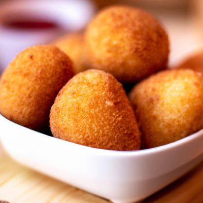 Imagem de uma porção de torresmo crocante e dourado em um prato branco. Eles são feitos com fatias finas de barriga de porco e cozidos na Airfryer, resultando em uma textura crocante e saborosa.