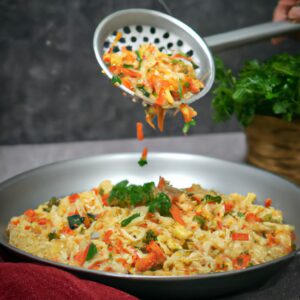 Imagem de um prato com macarrão cozido acompanhado de vários legumes coloridos, como brócolis, cenoura, pimentão e cebola, todos preparados em uma Airfryer.