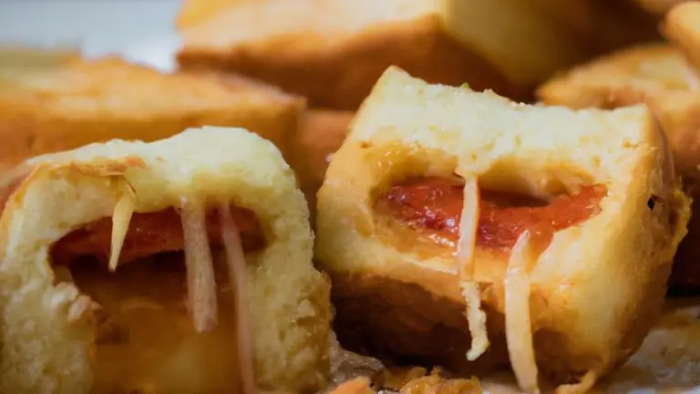 Uma fotografia de um prato com pão à parmegiana feito na airfryer. O pão está dourado e coberto com queijo derretido e molho de tomate.