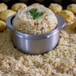 Imagem de um prato com arroz integral cozido na Airfryer. O arroz é marrom claro e tem uma textura fofa. Está coberto com ervas frescas e acompanhado de uma fatia de limão.