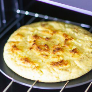 Imagem de uma torta de abobrinha assada em uma Airfryer. A torta tem uma crosta dourada e é recheada com abobrinha ralada, queijo, ervas e especiarias.