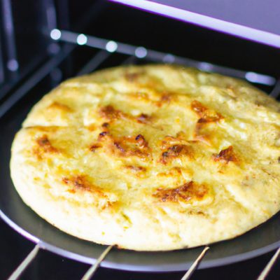 Imagem de uma torta de abobrinha assada em uma Airfryer. A torta tem uma crosta dourada e é recheada com abobrinha ralada, queijo, ervas e especiarias.