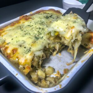 Imagem de uma lasanha vegetariana crocante e dourada, feita na Airfryer. A lasanha tem camadas de massa, vegetais grelhados, queijo derretido e molho de tomate.