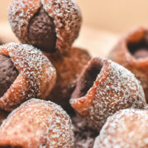 Imagem de um livro de receitas com o título "Receitas Na Airfryer Doce". O livro é azul claro e tem uma imagem de uma airfryer com doces assados dentro.