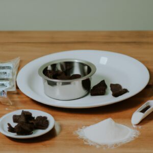 Imagem mostra uma pessoa usando uma airfryer para derreter chocolate. O chocolate é colocado em um recipiente dentro da airfryer e derrete gradualmente, criando uma textura cremosa e uniforme.