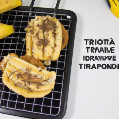 Imagem de um sanduíche de banana cortado ao meio em uma tábua de madeira. Os dois pedaços de pão são dourados e crocantes, e o recheio de banana é visível no centro. O sanduíche é guarnecido com mel e nozes picadas.