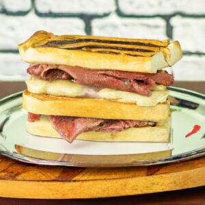 Imagem mostra um sanduíche de churrasco preparado em uma airfryer, com pão crocante, suculenta carne de churrasco, queijo derretido e molho barbecue. O sanduíche é cortado ao meio, revelando seu interior delicioso e apetitoso.