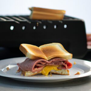 Imagem de um sanduíche de carne grelhada em pão francês, cozido em uma airfryer. O sanduíche é servido em um prato com fatias de batata frita.