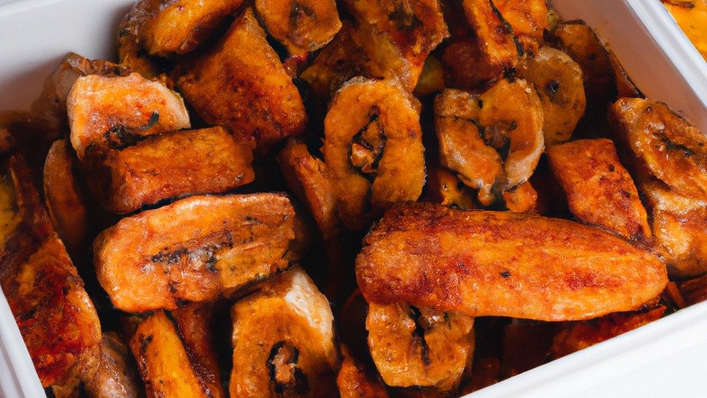 Imagem de uma bandeja de Airfryer com fatias de banana cobertas com canela e açúcar mascavo. As bananas são douradas e crocantes, com uma leve camada de especiarias por cima.