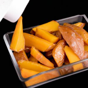 Imagem de batatas doces cortadas em palitos finos e douradas em uma airfryer. O prato é servido com um molho cremoso à base de iogurte ao lado.