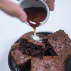 Imagem de um brownie de chocolate rico e decadente feito em uma airfryer. O brownie tem uma crosta crocante e um interior macio e fudgy. É coberto com uma camada de glacê de chocolate e polvilhado com nozes picadas.