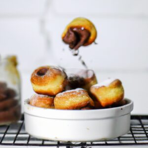 Imagem de um suflê de Nutella recém-assado em uma airfryer. O suflê é marrom dourado e arejado, com uma crosta crocante e um interior cremoso e derretido. A airfryer é mostrada ao fundo.