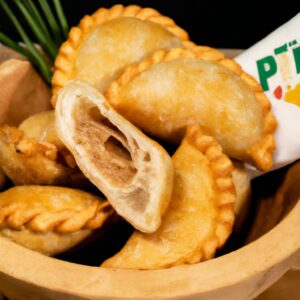 Foto de tilápias empanadas crocantes e douradas cozinhando em uma airfryer. A imagem mostra os filés de peixe empanados em uma cesta de airfryer, com um fundo de limão, salsa e coentro.