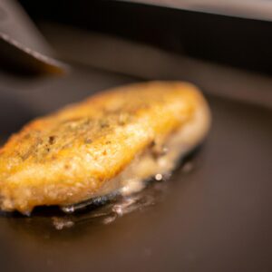 Imagem de tilápia frita na Airfryer, com manteiga derretida por cima. A tilápia é dourada e crocante, com um interior branco e escamoso.