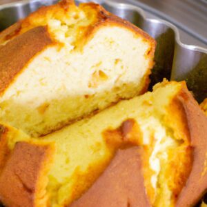 Imagem de uma torrada de bolo crocante e dourada feita em uma Airfryer, com gotas de glacê escorrendo pelas laterais. A torrada é coberta com uma cobertura de migalhas e decorada com frutas vermelhas frescas.