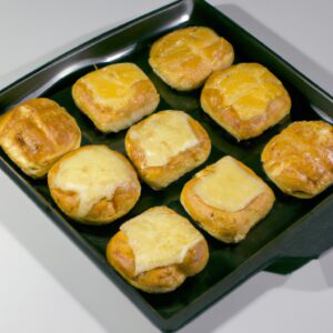 Imagem de torradinhas douradas e crocantes preparadas na airfryer, servidas em um prato branco. As torradinhas são polvilhadas com sal e pimenta e têm um toque de manteiga derretida.