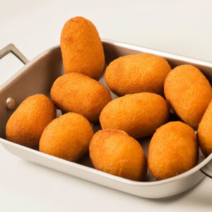 Uma fotografia aérea de uma Air Fryer Britânia Bella Cuccina em uma bancada de cozinha branca. A fritadeira de ar é preta e tem um cesto antiaderente. Há um livro de receitas ao lado da fritadeira de ar.