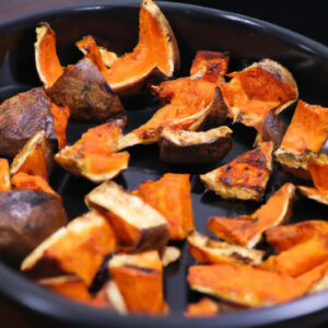 Imagem de uma abóbora assada na Airfryer. A abóbora é cortada ao meio e assada com azeite, sal e pimenta. A abóbora tem uma pele crocante e um interior macio e amanteigado.