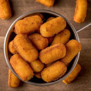 Imagem de uma fritadeira Air Fryer branca com uma cesta de metal removível cheia de batatas fritas douradas. O texto na imagem diz "O Melhor Blog Sobre Air Fryer".