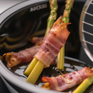 Uma imagem de aspargos verdes brilhantes e bacon crocante cozidos em uma airfryer. Os aspargos são longos e finos, com pontas tenras. O bacon está cortado em fatias finas e enrolado em torno dos aspargos. A imagem é nítida e vibrante, e o fundo é branco.
