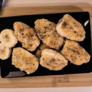 Imagem de banana à milanesa na airfryer, com cobertura crocante e dourada, servida em um prato com folhas de hortelã como decoração.