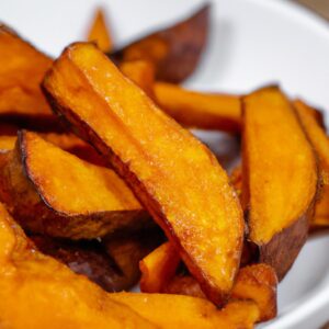 Imagem de batatas-doces caramelizadas crocantes e douradas cozidas na Airfryer. As batatas são cortadas em palitos ou fatias finas e cobertas com uma mistura doce e caramelizada. O exterior é crocante e o interior é macio e delicioso.