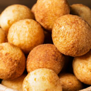 Imagem de bauruzinhos dourados e crocantes cozidos em uma airfryer. Os bauruzinhos têm uma crosta externa crocante e um interior macio e fofo, e são servidos em um prato com um mergulho de sua escolha.