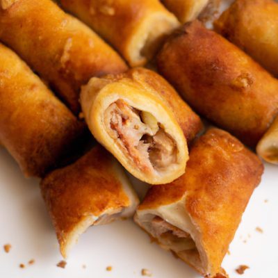 Imagem de três variedades de baurus recheados com queijo processado derretido e servidos em um prato. O bauru à esquerda tem uma fatia de presunto e é chamado de "Joelho". O bauru central tem uma fatia de salame e é chamado de "Americano". O bauru à direita é enrolado e é chamado de "Enroladinho". Todos os baurus foram preparados em uma airfryer.