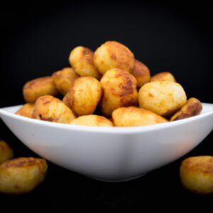 Foto de bolinhos de batata com calabresa cozidos na Airfryer. Os bolinhos têm formato redondo e estão dourados. São servidos em um prato com uma tigela de molho de tomate ao lado.