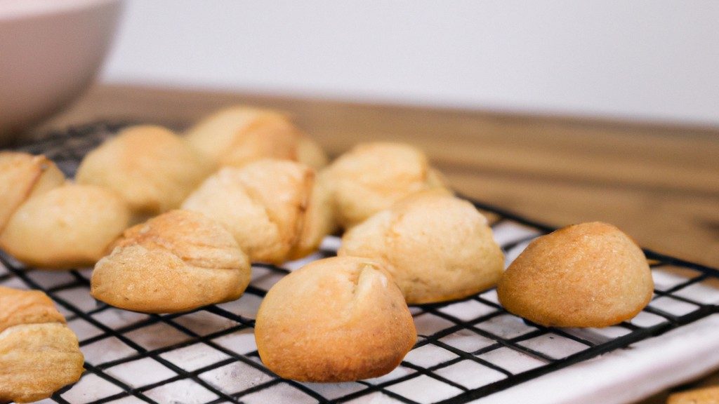 Bolinhos De Cookie Na Airfryer 1 Uma imagem de bolinhos de cookie dourados e crocantes recém-saídos de uma Airfryer. Os bolinhos são cobertos com gotas de chocolate e estão dispostos em um prato branco.