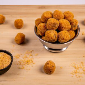 Uma foto de bolinhos de lentilhas dourados e crocantes, servidos em uma tigela com um molho de iogurte ao lado. Os bolinhos são feitos com lentilhas, cebola, alho, especiarias e ervas, e são cozidos na Airfryer até ficarem crocantes por fora e macios por dentro.