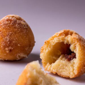 Imagem de um bolo de mandioca ou aipim redondo e dourado, cozido em uma Airfryer. O bolo é coberto com uma crosta crocante e tem um centro macio e úmido.