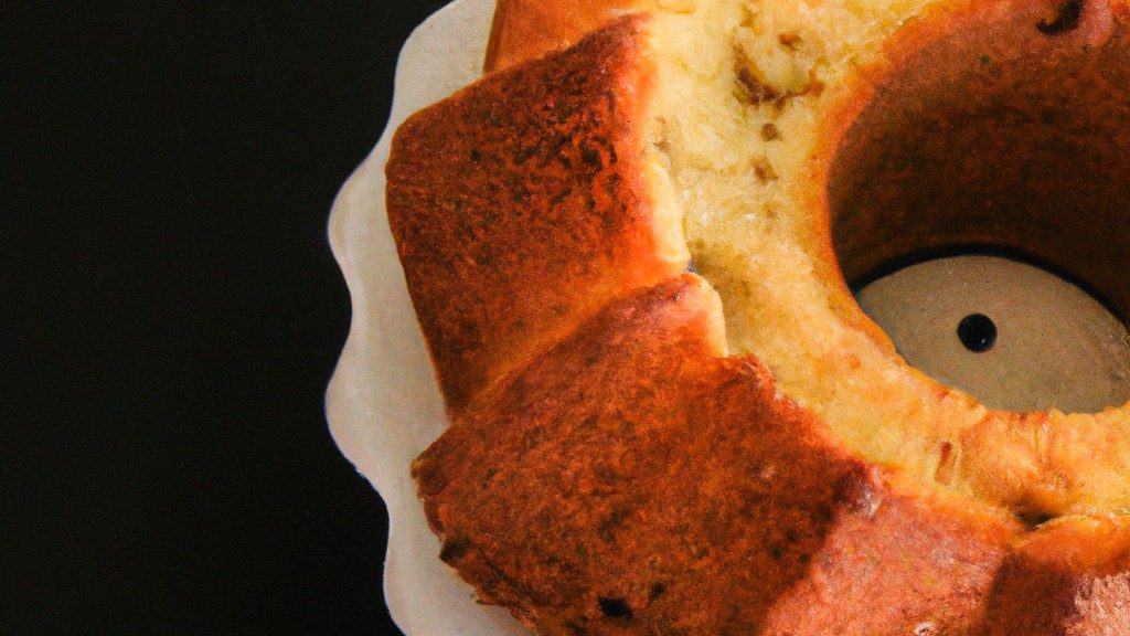 Bolo Na Airfryer 1 Imagem de um bolo redondo e dourado cozido em uma airfryer. O bolo é coberto com uma cobertura de chocolate e granulado colorido.