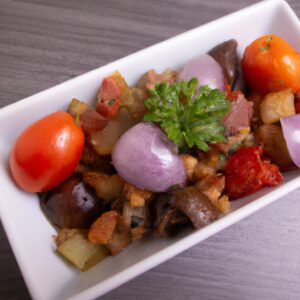 Imagem de uma travessa cheia de Caponata Antepasto feita na Airfryer. A Caponata é uma mistura de berinjela em cubos, pimentão, cebola, aipo e azeitonas pretas. É coberto com uma crosta crocante de pão ralado e queijo parmesão. O prato é servido com pão torrado ou biscoitos.