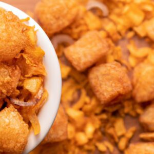 Imagem de cebolas cortadas em rodelas e empanadas em uma tigela, prontas para serem colocadas na Airfryer. A legenda diz "Cebola Frita Crocante Na Airfryer (Crispy)".