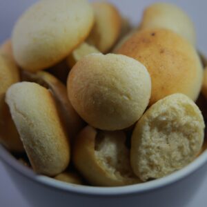 Imagem de uma cesta de Airfryer cheia de Chipas, um pãozinho de queijo brasileiro, recém-assados e dourados. Eles estão dispostos em camadas, mostrando sua textura crocante e interior macio. A imagem transmite o aroma e o calor do pão recém-assado.