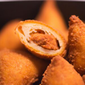 **Descrição do Alt da Imagem:**

Uma imagem de coxinhas da asa crocantes e douradas cozidas na Airfryer. Elas estão organizadas em um prato branco com um fundo azul. A imagem mostra o exterior crocante e o interior suculento das coxinhas da asa.