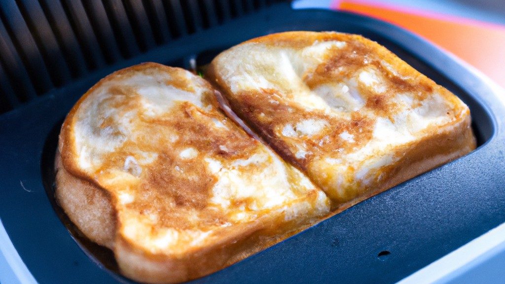 Imagem de uma airfryer com torradas douradas dentro. A airfryer é preta e tem uma cesta de metal. As torradas são grossas e crocantes.