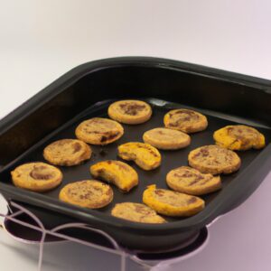 Uma foto de close-up de cookies de Sucrilhos preparados na Airfryer. Os cookies são dourados e crocantes, com pedaços de Sucrilhos ainda visíveis na superfície. Eles são servidos em um prato branco com um garfo.