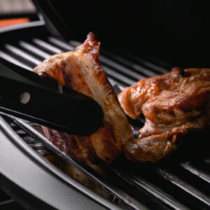 Imagem de costelinhas de porco assadas em uma airfryer. As costelinhas são douradas e crocantes, com gotas de molho barbecue escorrendo.